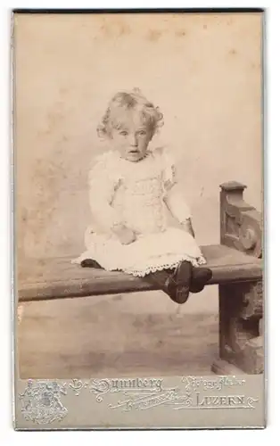 Fotografie E. Synnberg, Luzern, Bruchstr. 22, Süsses kleines Mädel im weissen Kleidchen sitzt auf Bank