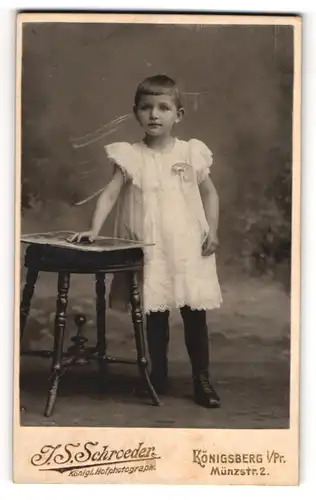 Fotografie Joh. Steph. Schroeder, Königsberg i. Pr., Münzstr. 2, Kind im weissen Kleid mit einem Bilderbuch