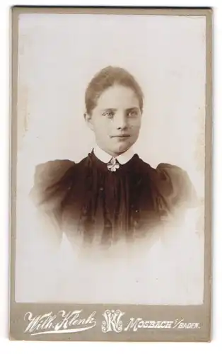 Fotografie Wilh. Klenk, Mosbach /Baden, Junges Mädchen in dunklem Kleid mit Puffärmeln und Glücksklee-Brosche