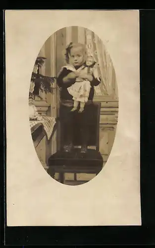 Foto-AK Mädchen steht mit ihrer Puppe auf einem Stuhl