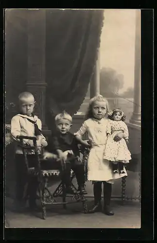 AK Drei Kinder mit Puppe und unterschiedlichen Expressionen im Gesicht