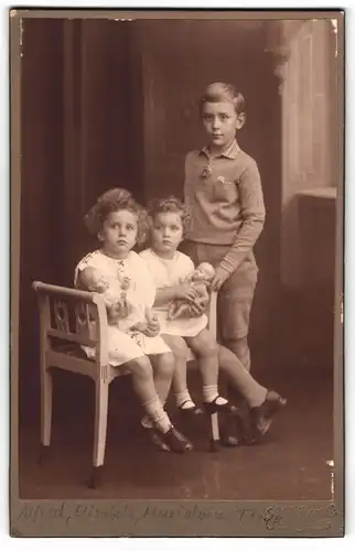 Fotografie L. Bäuerle, Tübingen, Portrait Grosser Bruder mit seinen zwei niedlichen Schwestern samt Puppen im Arm