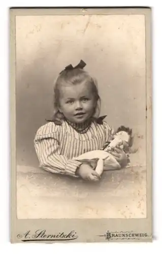 Fotografie A. Sternitzki, Braunschweig, niedliches kleines Mädchen im gestreiften Kleid mit ihrer Puppe