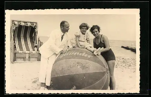 Foto-AK Herr im Anzug, Dame im Badeanzug und Kind im Kleid mit Luftball am Strand