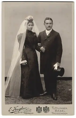 Fotografie E. Kugler, Tuttlingen, Ehepaar Arm in Arm mit schwarzem Brautkleid und Anzug mit Zylinder
