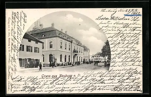 AK Neuburg a. D., Strassenpartie mit Menschenschlange vor grossem Gebäude