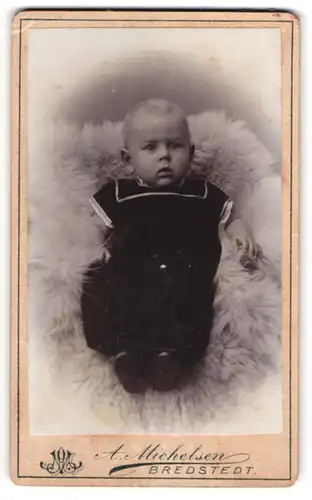 Fotografie A. Michelsen, Bredstedt, Portrait süsses Baby im Matrosenanzug auf Fell liegend