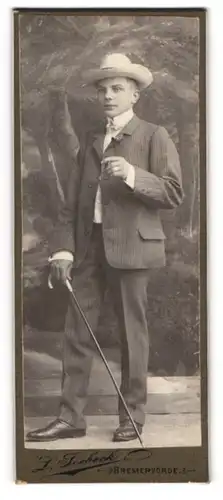 Fotografie L. Seebeck, Bremervörde, Portrait junger Mann im karierten Anzug mit Flanierstock und Hut, Dandy