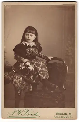 Fotografie A. W. Kraatz, Berlin, junges Mädchen im karierten Kleid mit Blumenkörbchen sitzend auf dem Tisch