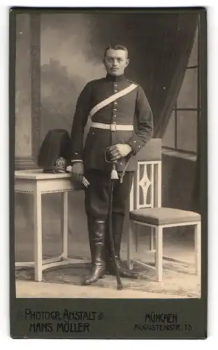 Fotografie Hans Möller, München, Augustenstr. 75, junger Soldat in Uniform mit Pickelhaube Rosshaarbusch auf dem Tisch
