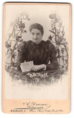 Fotografie A. Drawe, Berlin, Frau im dunklen Kleid, im Weidekorb mit Blumen, Passepartout