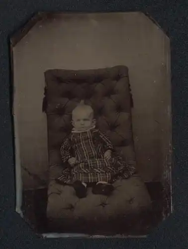 Fotografie Ferrotypie niedliches Kleinkind im karierten Kleid sitzt auf Sessel