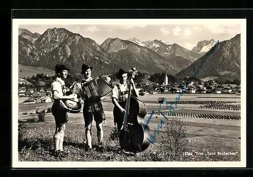 AK Trio Toni Brutscher, mit Instrumenten in Trachten vor der Stadt Oberstdorf, Blick zur Kirche