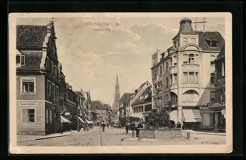 AK Offenburg i. B., Hauptstrasse mit Geschäften, Kirchturm und Brunnen