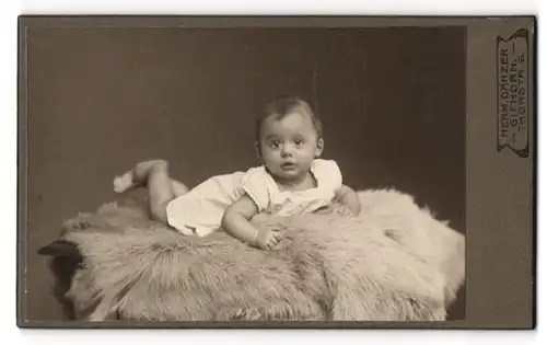 Fotografie Herm. Dänzer, Gifhorn, Thorstrasse 6, Kleinkind im Kleidchen auf einen Fell