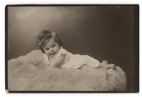 Fotografie unbekannter Fotograf und Ort, Kleinkind liegt auf einem Pelz
