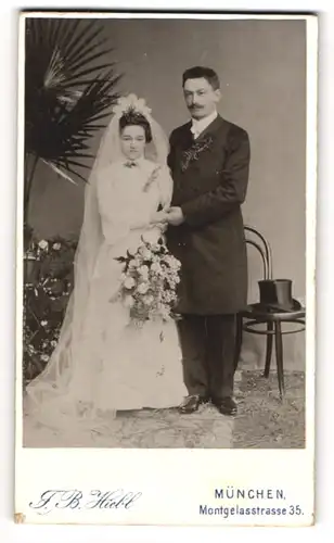 Fotografie J. B. Hiebl, München, bayrisches Brautpaar im Hochzeitskleid, Zylinder auf dem Stuhl