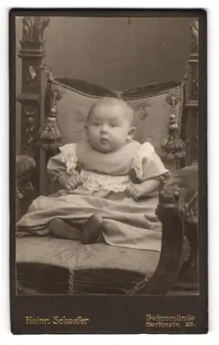 Fotografie Heinr. Schaefer, Swinemünde, Gartenstr. 26, Portrait niedliches Baby im gerüschten Kleidchen