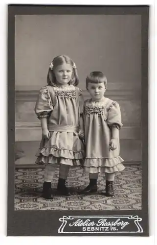 Fotografie Atelier Rossberg, Sebnitz i. Sa., Süsses Geschwisterpaar in niedlichen Kleidern