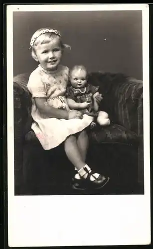 Fotografie blondes Mädchen mit Puppe auf Sessel sitzend, Doll, Dolly