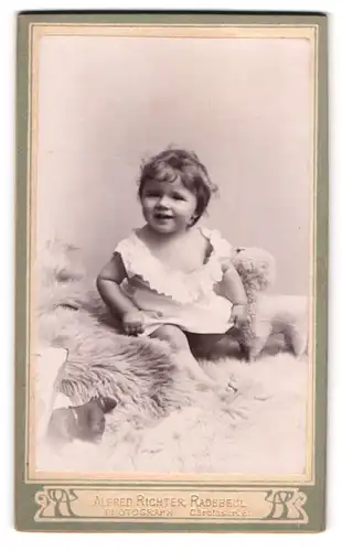 Fotografie Alfred Richter, Radebeul, Carolastr. 5, Süsses Kleinkind im Hemd sitzt auf Fell