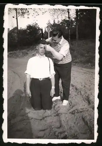 Fotografie Bursche rasiert seinem Kumpel den Kopf