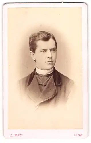 Fotografie A. Red, Linz, junger Pastor im Anzug mit Collar