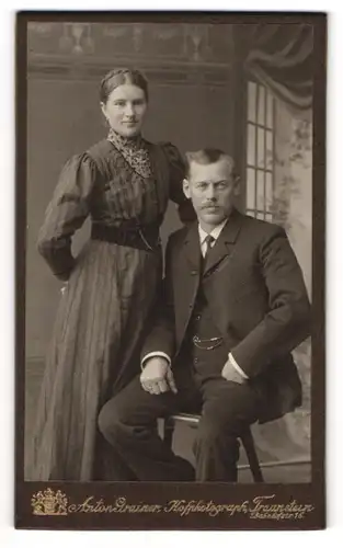 Fotografie Anton Grainer, Traunstein, Bahnhofstr. 16, stehende Dame mit Lächeln neben sitzendem Herren mit Schnauzbart