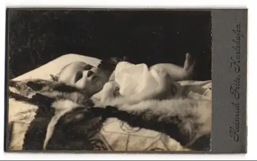 Fotografie Heinrich Fritz, Karlshafen, Süsses Kleinkind im Hemd liegt auf einem Fell