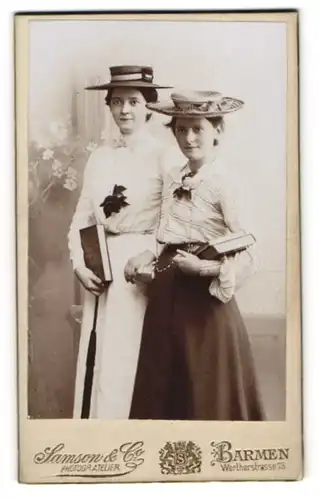 Fotografie Samson & Co., Barmen, zwei hübsche junge Damen in Sommerkleidern mit Lehrbüchern im Arm