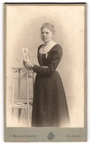 Fotografie J. Benade, Cassel, Königstrasse 27, Bürgerliches Fräulein im schlichten Kleid hält eine Fotografie