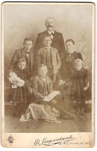 Fotografie Chr. Langenschwadt, Kiel, Annen Strasse 62, Paar mit drei Jungen und zwei Mädchen im Sonntagsstaat, Puppe