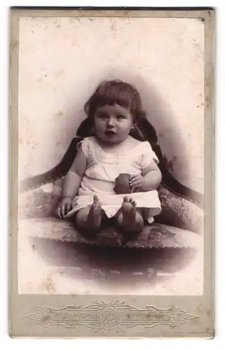 Fotografie F. Zinck, Hildburghausen, Kleinkind mit Ponyfrisur auf einem Sessel