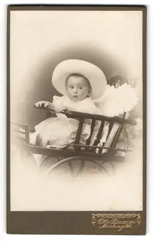 Fotografie Otto Damm, Marburg, Baby mit breitkrempigem Hut in einem Wagen