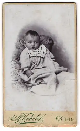 Fotografie Adolf Kubalek, Wien, Gersthoferstrasse 28, Baby mit schüchternem Blick in einem langen Kleid