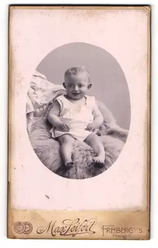 Fotografie Max Seifert, Freiberg i. S., Poststrasse 11, Lächelndes Kleinkind auf einem Fell