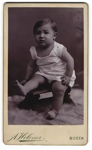 Fotografie A. Holzner, Bozen, Kaiser Franz Josef Strasse, Kleinkind im Strampler auf einem Bänkchen