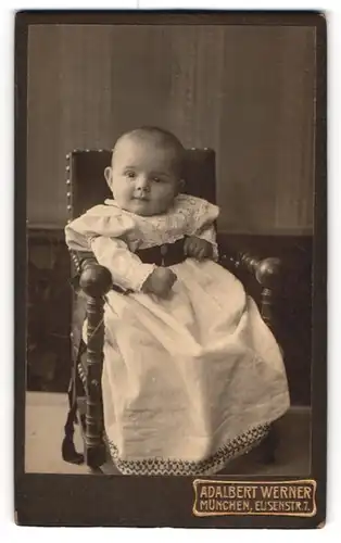 Fotografie Adalbert Werner, München, Elisenstrasse 7, Heiteres Baby im Taufkleid auf einem Stühlchen