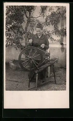 AK Frau arbeitet an einem Spinnrad