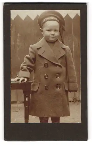 Fotografie unbekannter Fotograf und Ort, Kleiner Junge im Mantel mit Mützenband