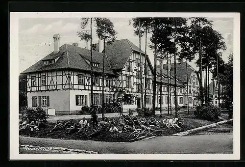 AK Grafenwöhr, Grosses Gebäude mit lagernder Soldatengruppe im Gras