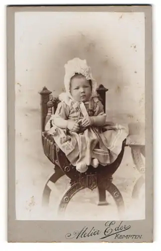 Fotografie Atelier Eder, Kempten, Kleinkind im Kleid mit Rüschenhaube auf einem Sessel