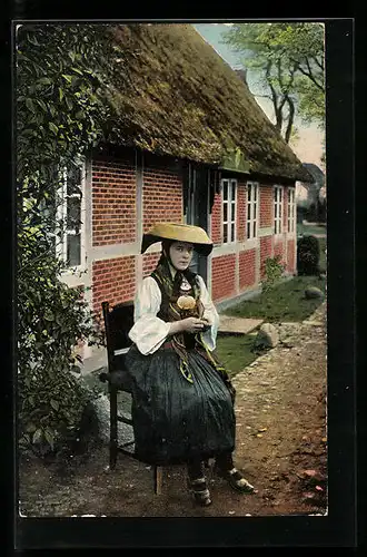 AK Junge Frau in Vierländer Tracht auf einem Stuhl vor dem Haus
