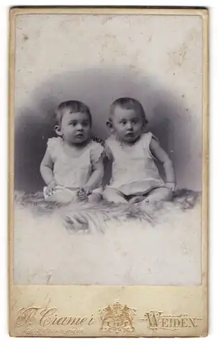 Fotografie F. Cramer, Weiden, Zwei Babys in Strampelkleidchen auf einem Fell
