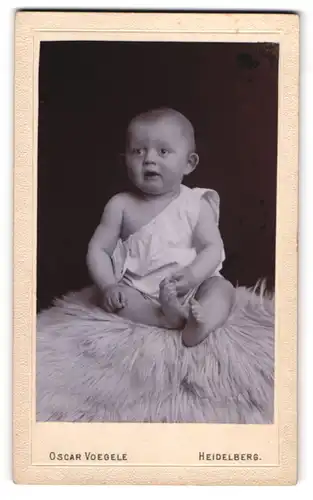 Fotografie Oscar Voegele, Heidelberg, Hauptstrasse 25, Baby mit ängstlichem Gesichtsausdruck auf einem Fell