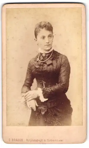 Fotografie C. Brasch, Berlin, Wilhelm-Strasse 57-58, Elegante junge Dame im engen Kleid mit Perlenkette und Brosche
