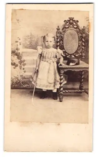 Fotografie unbekannter Fotograf und Ort, Kleinkind im Kleidchen mit Peitsche