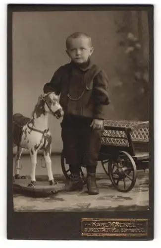 Fotografie Karl Mäckel, Burgstädt i. Sa., junger Knabe mit Schaukelpferd auf Rädern und Karren