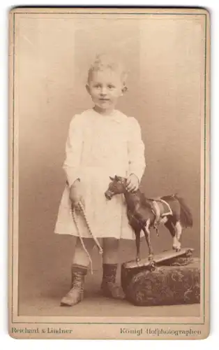 Fotografie Reichard & Lindner, Berlin, Mädchen mit Holzpferd auf Rollen im Atelier