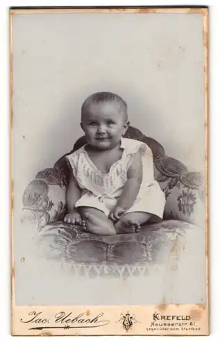 Fotografie Jac. Uebach, Krefeld, Neusserstr. 61, Lachendes Kleinkind auf einem Sessel
